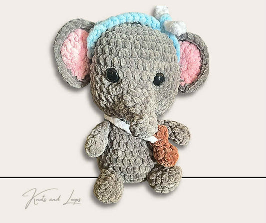 Crocheted toy elephant with a white ribbon on a light gray background